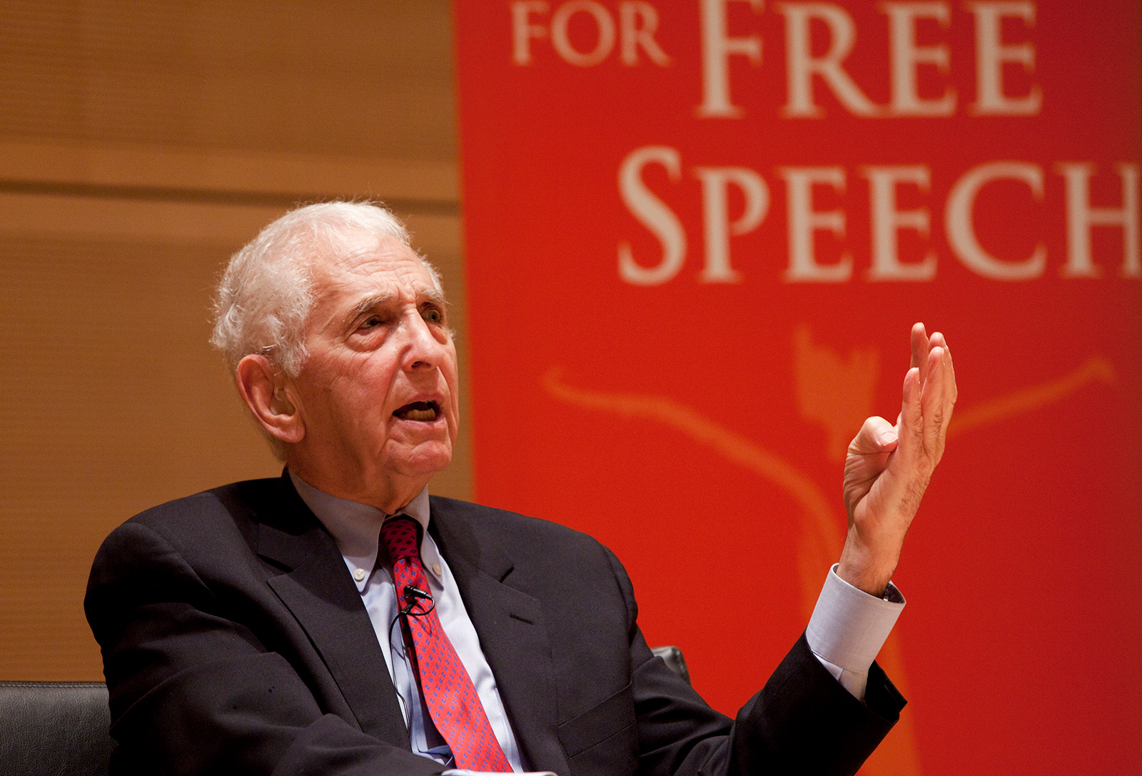 A man gestures while speaking during a lecture