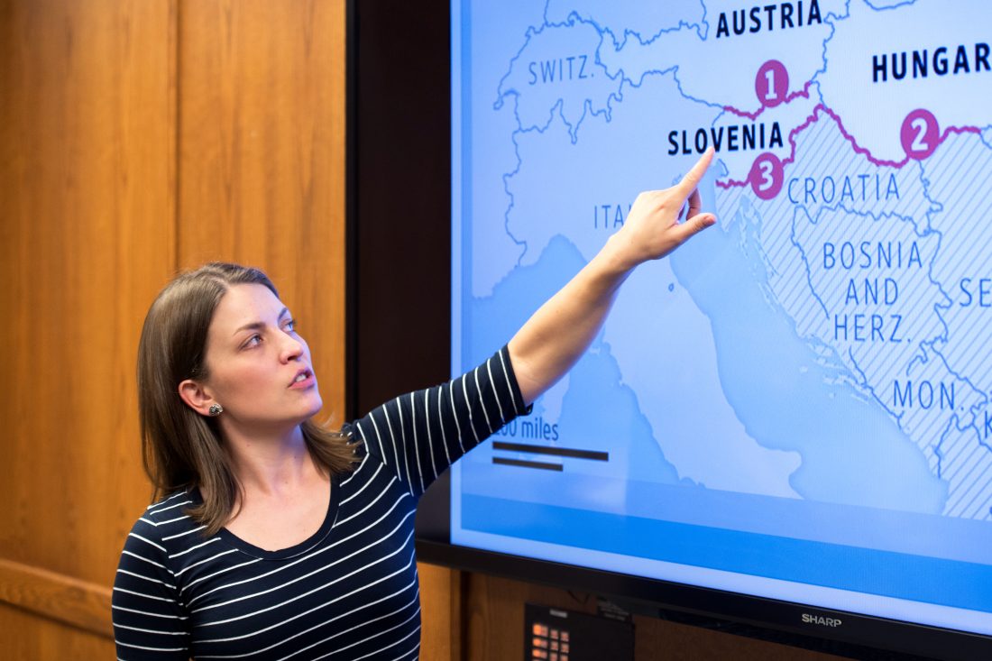 Female graduate student points to Slovenia on a map