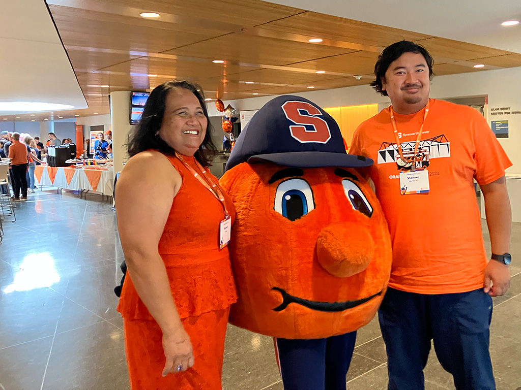 two people pose with a mascot