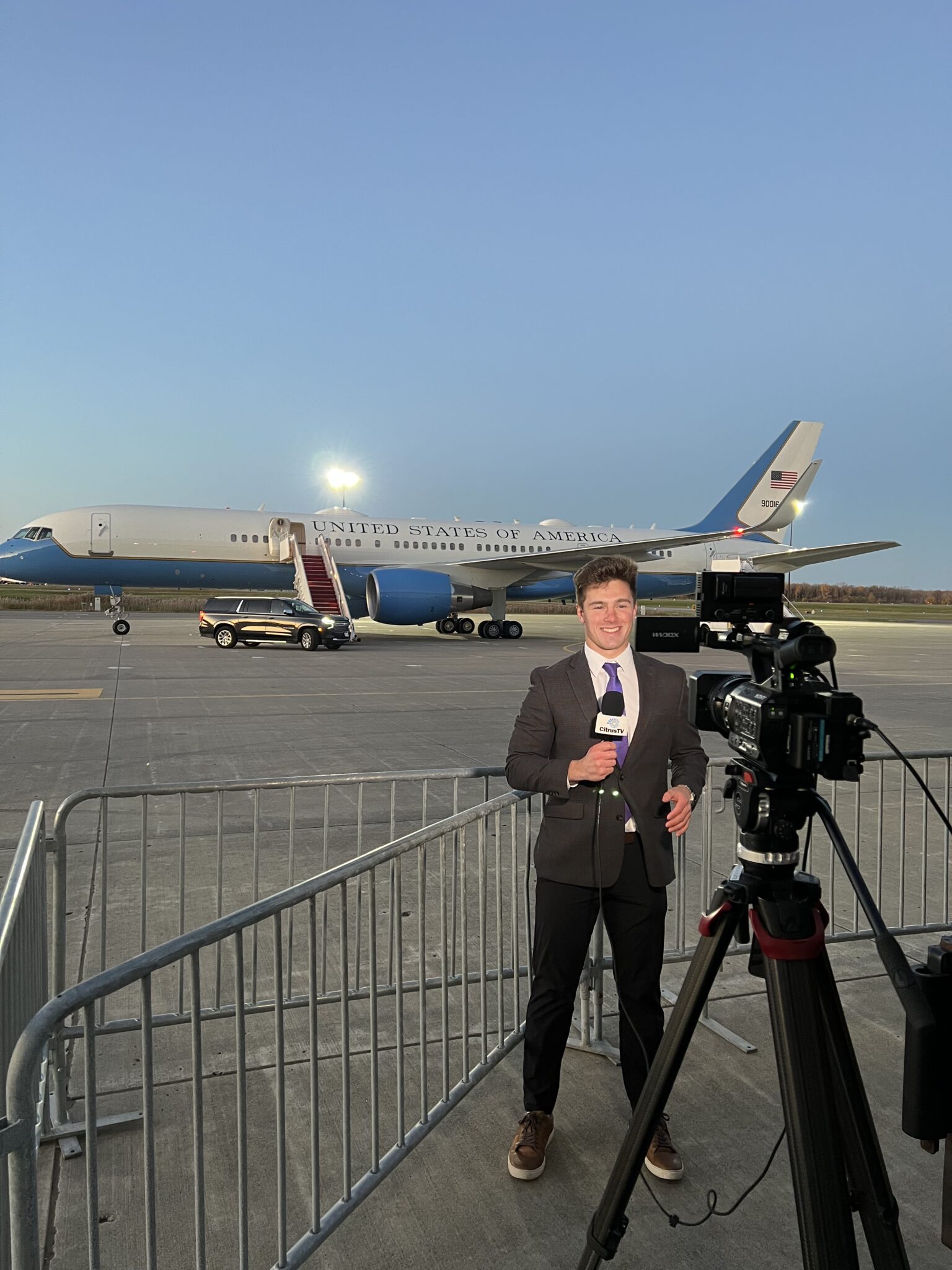 A reporter stands on a tarmac, reporting on Air Force One