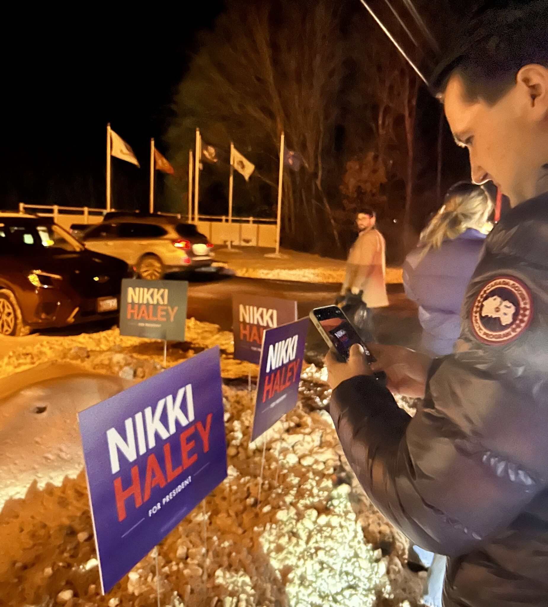 a person takes a photo on their cell phone of a presidential campaign sign