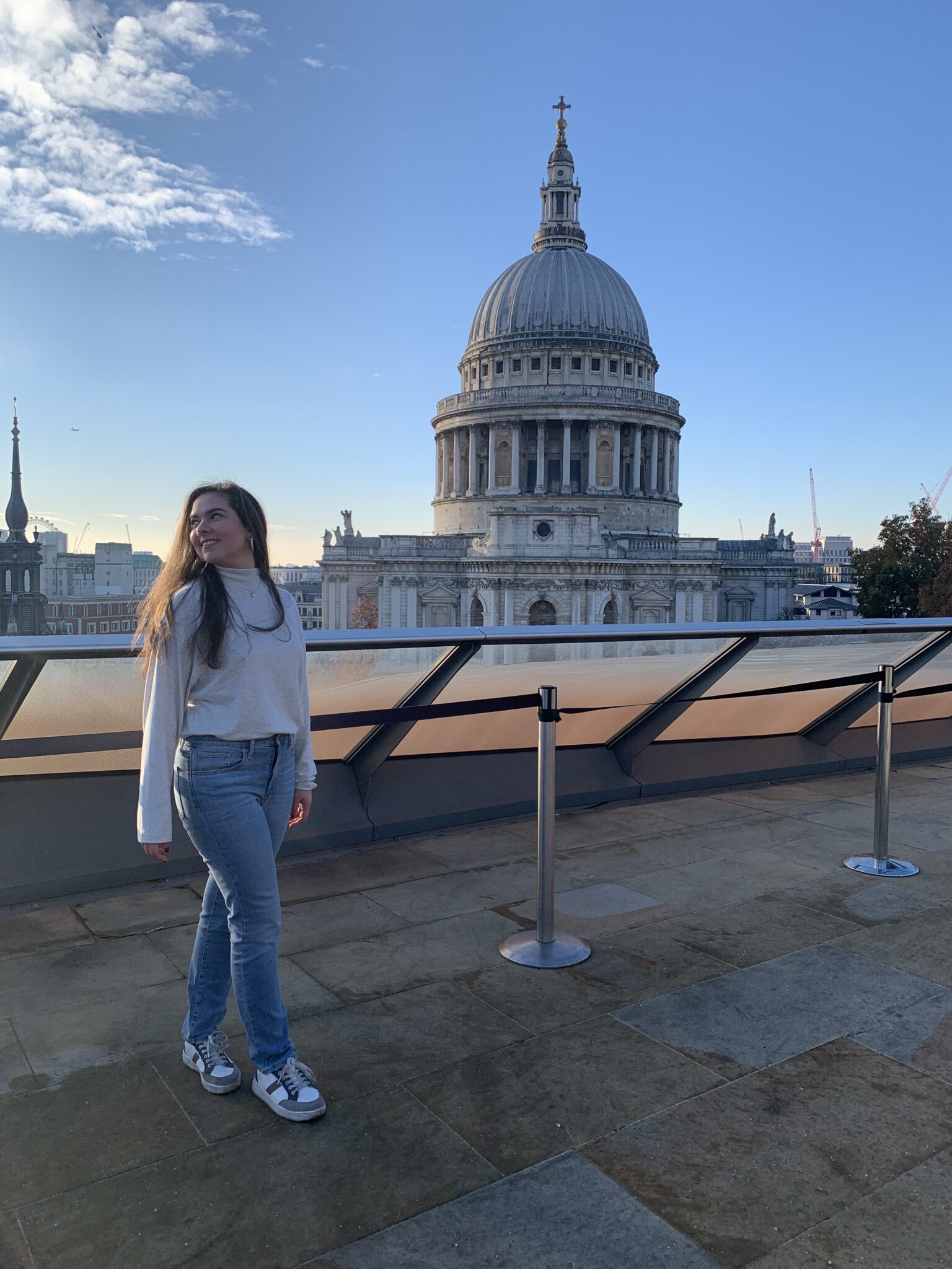 a person stands and smiles in front of St. Paul's Cathedral in London