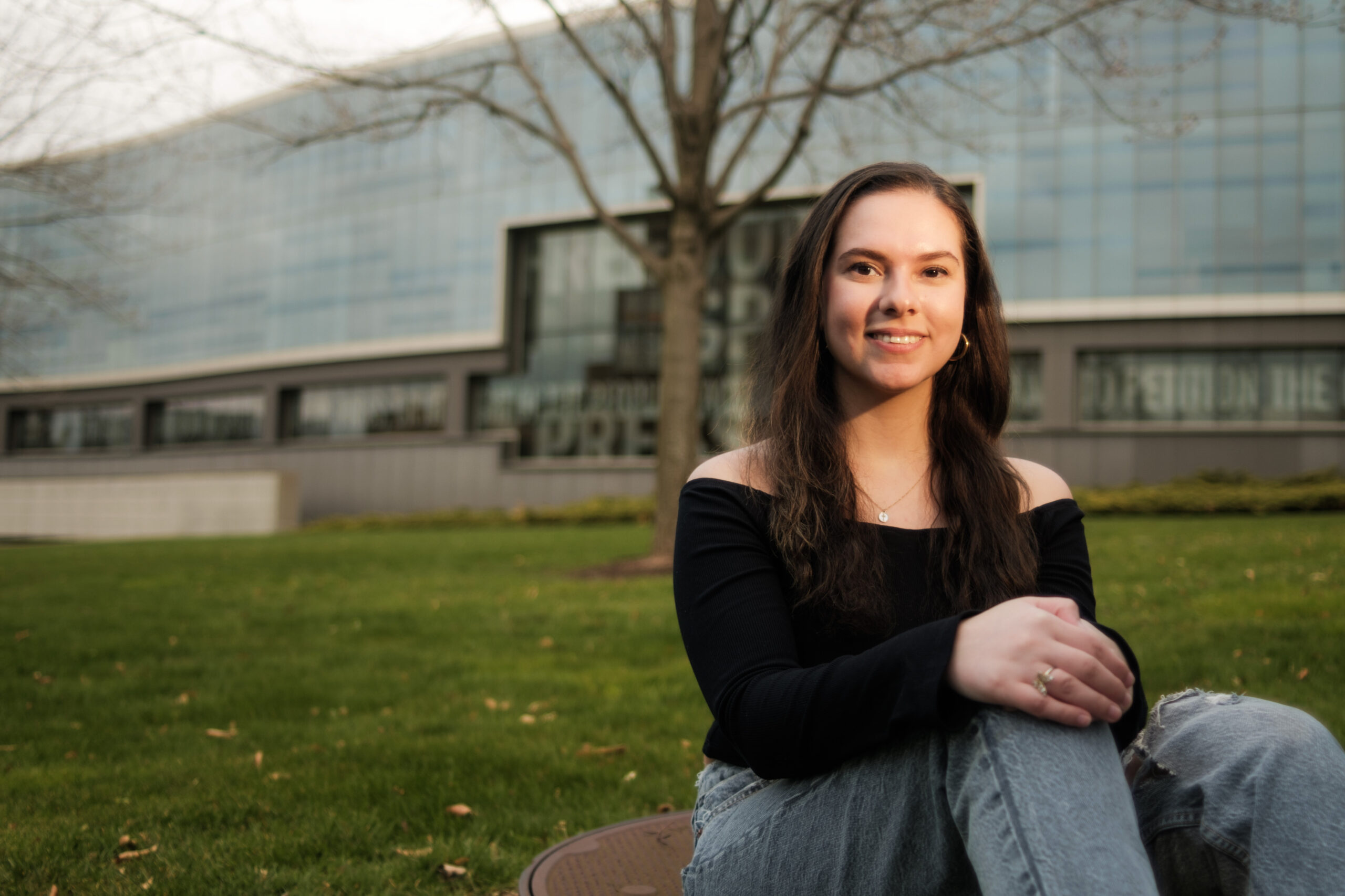 a person sits in the grass in front of a building