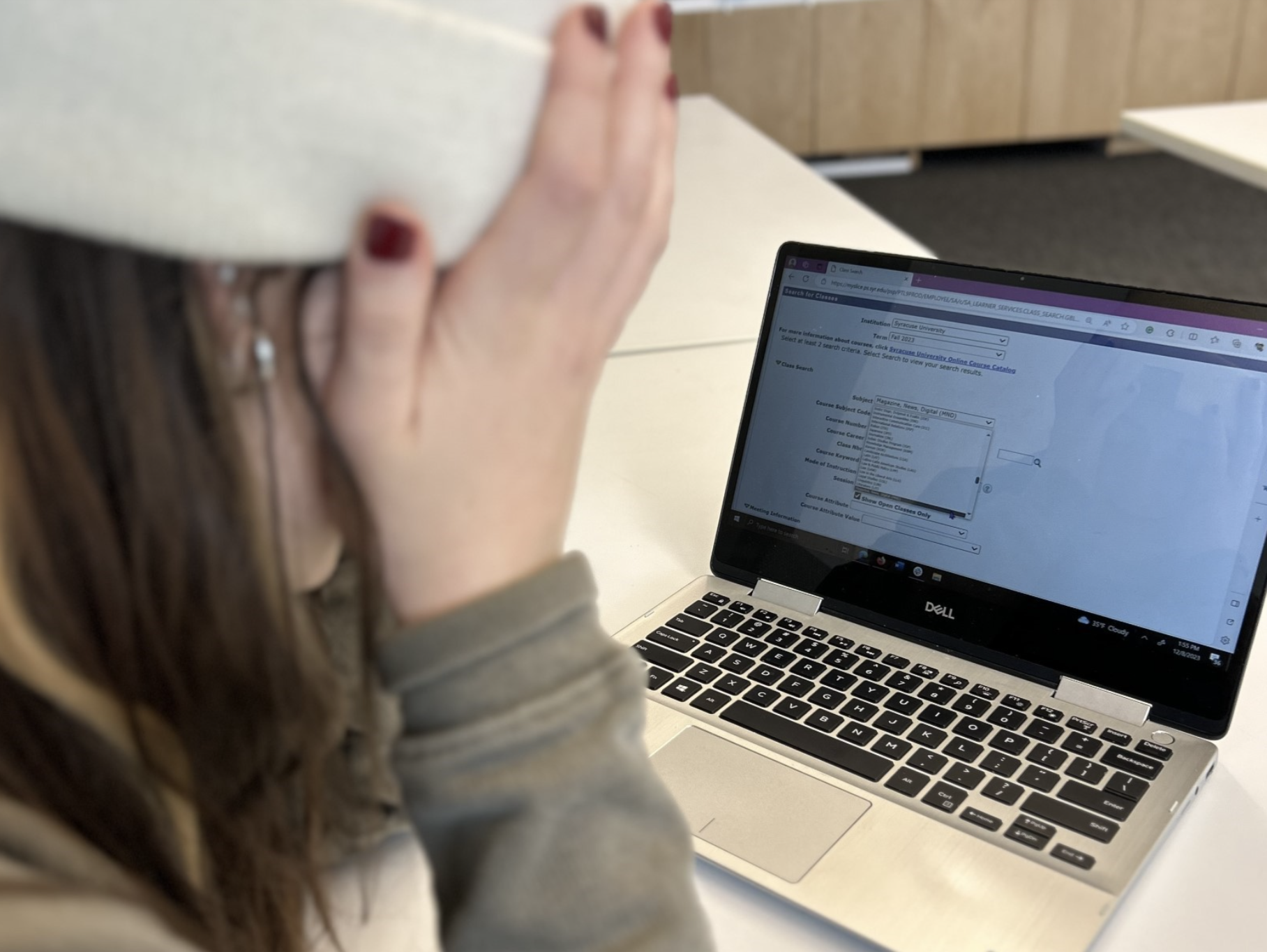 a person with their head in their hands looks at a computer screen