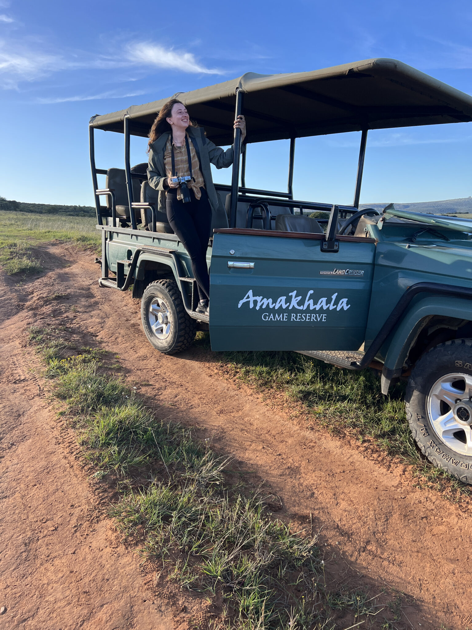 a person hangs out of a safari vehicle on a game reserve