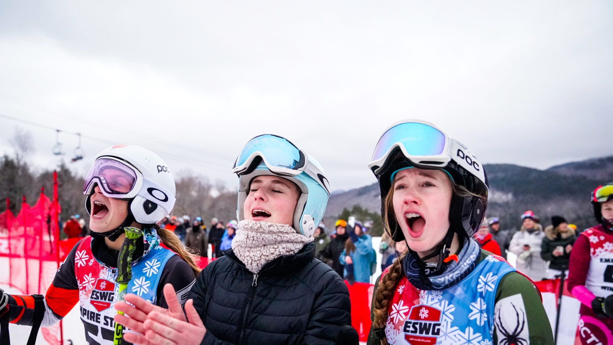 three young skiers cheer on a teammate