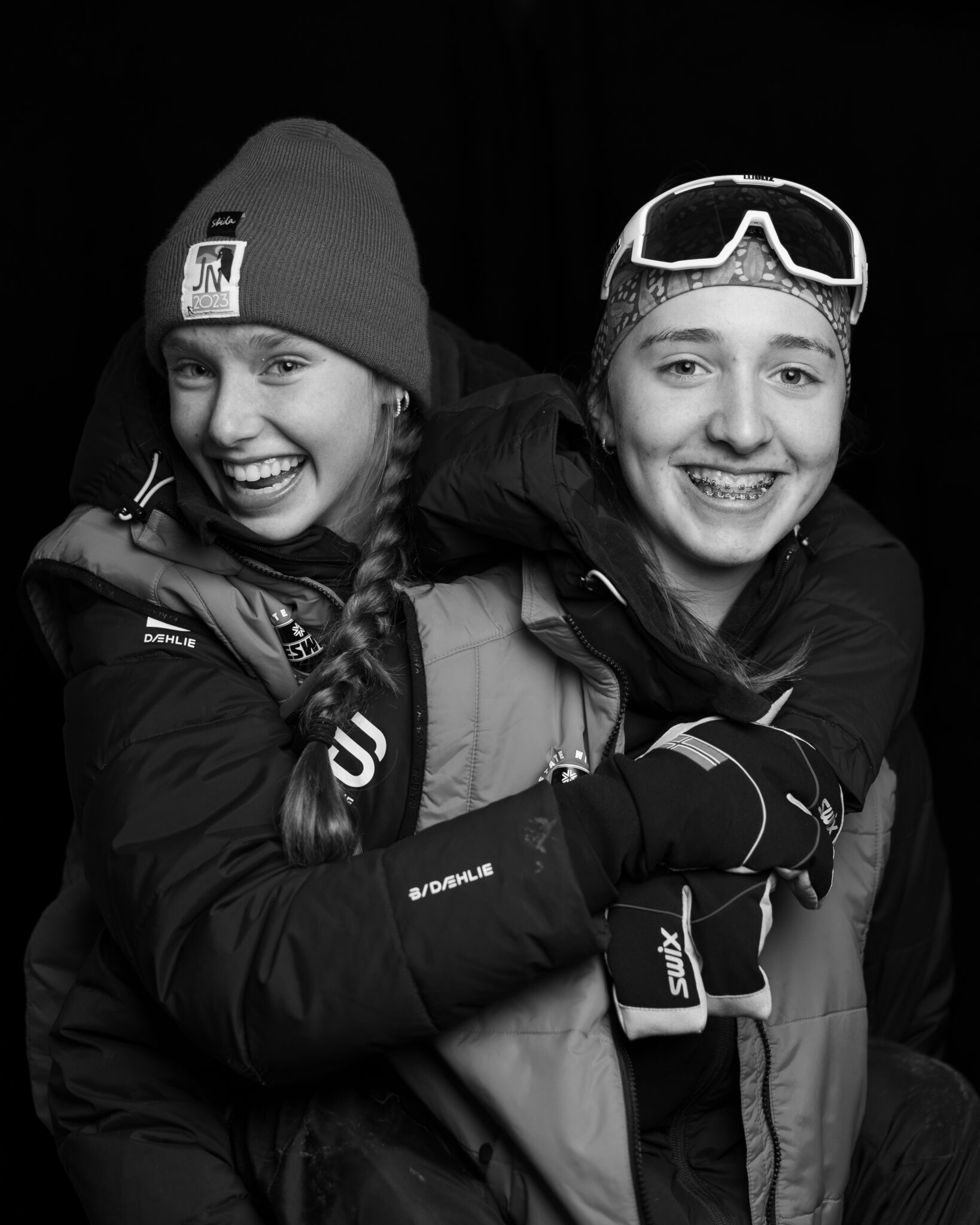 two people in winter gear hug each other and smile