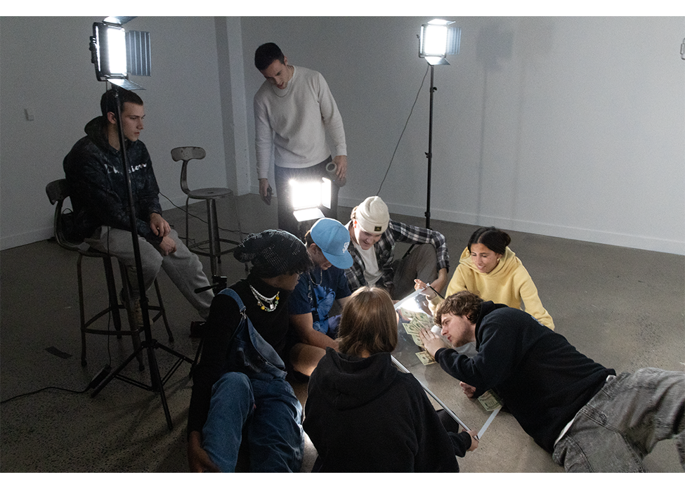a group of people film a music video with some sitting on the floor and some standing