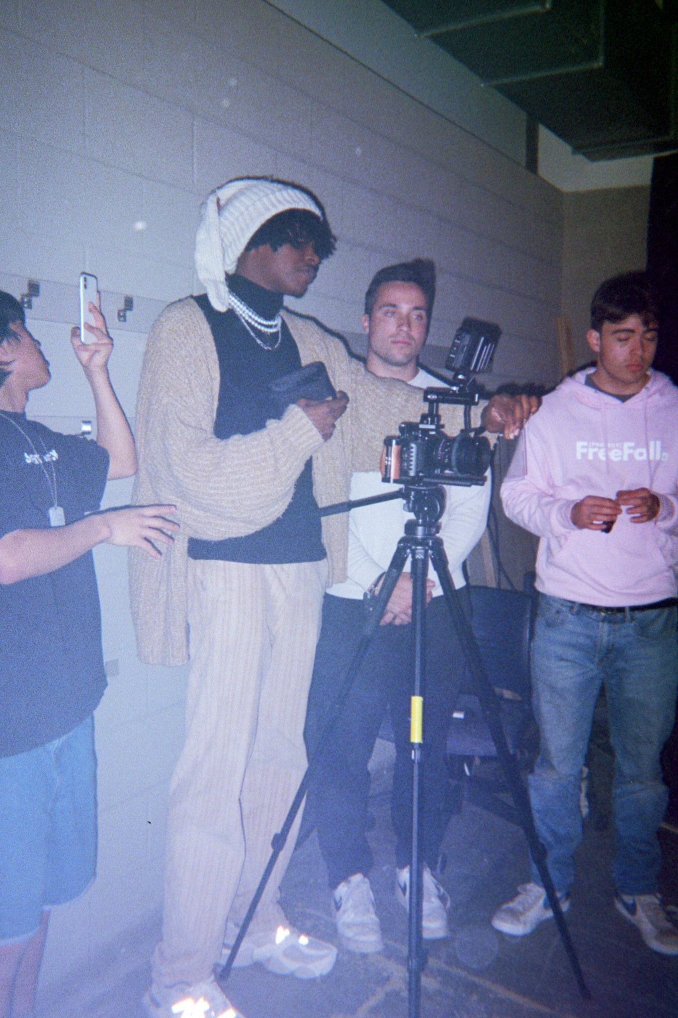 four people stand behind a camera as they film a music video