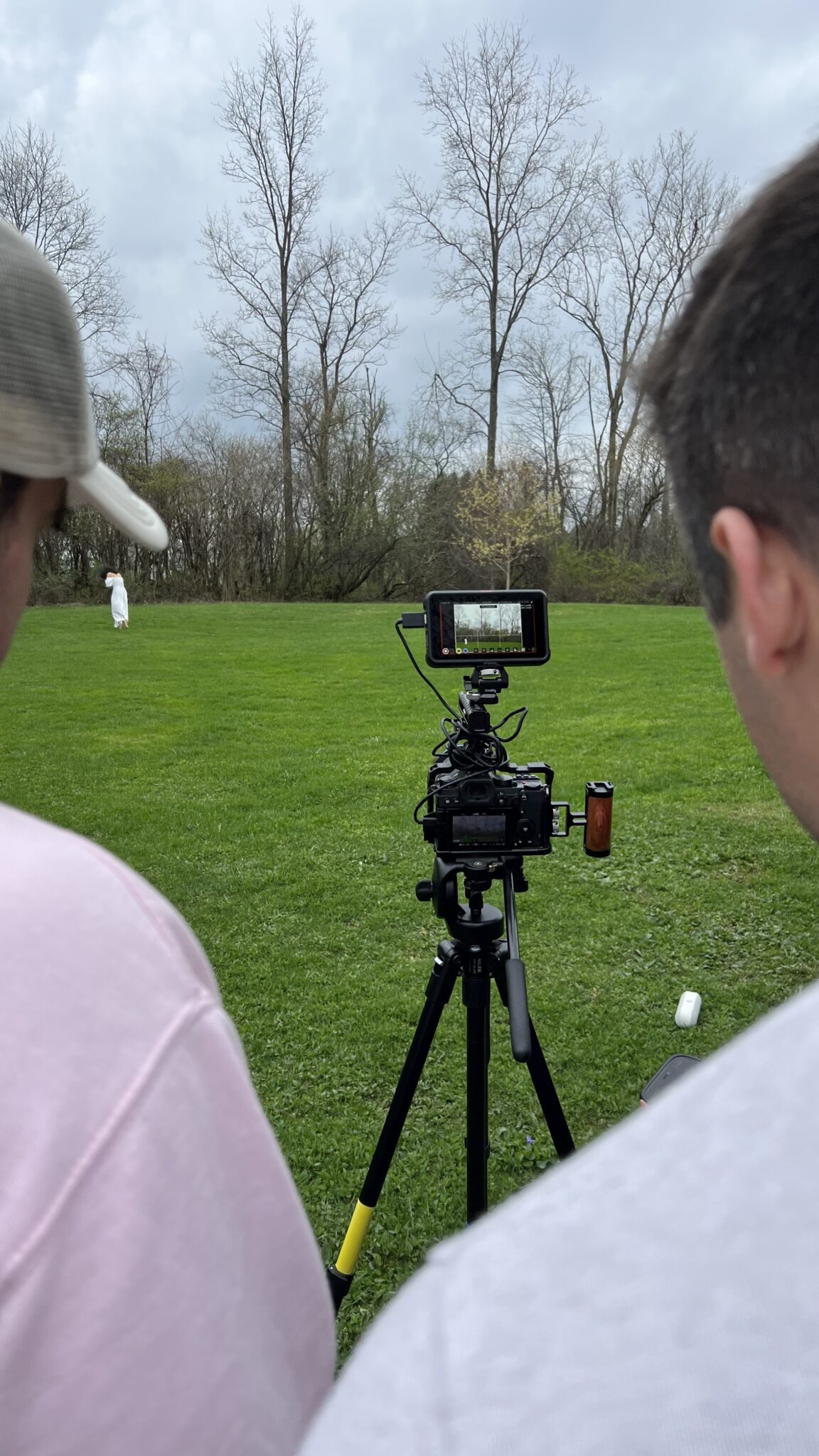 two people stand behind a camera as they film a music video