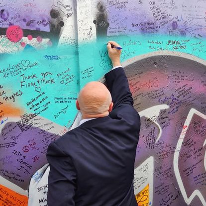 a person signs the Peace Wall in Belfast Northern Ireland