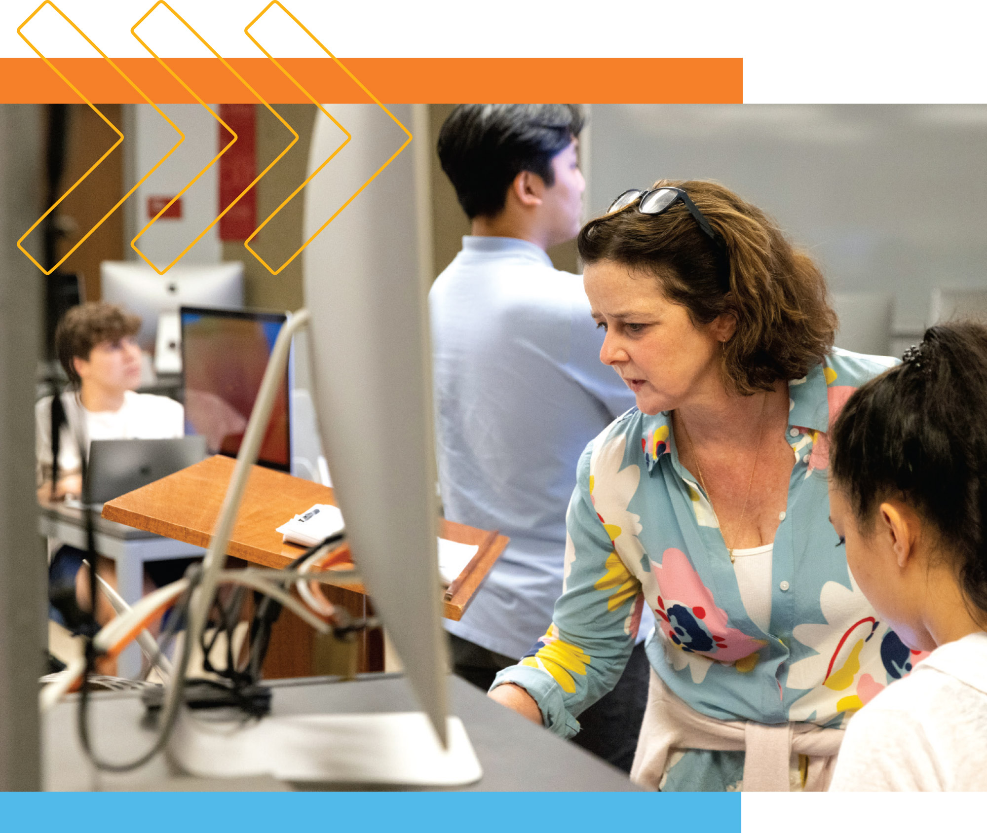 a person collaborates with students in front of a computer