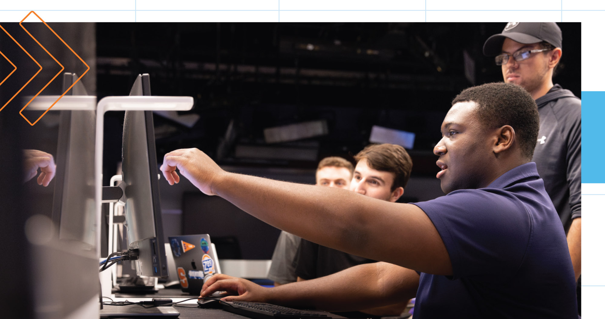 Students collaborating with each other in front of a computer screen.