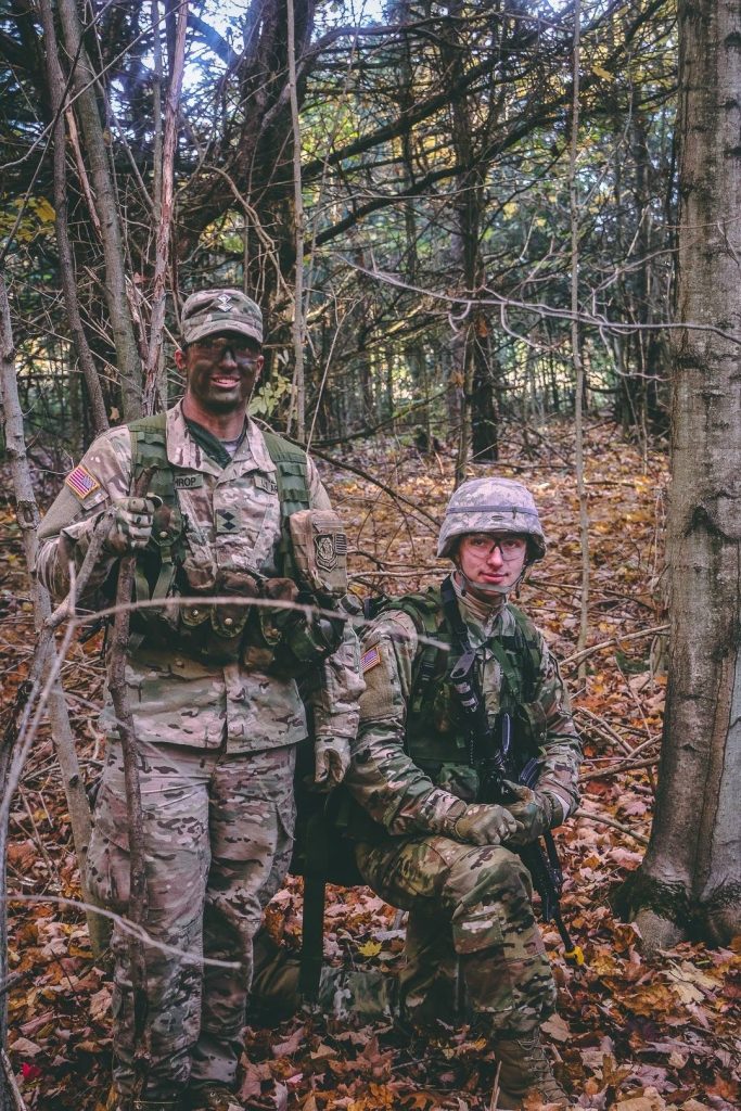 two military personnel participate in a training exercise in the woods