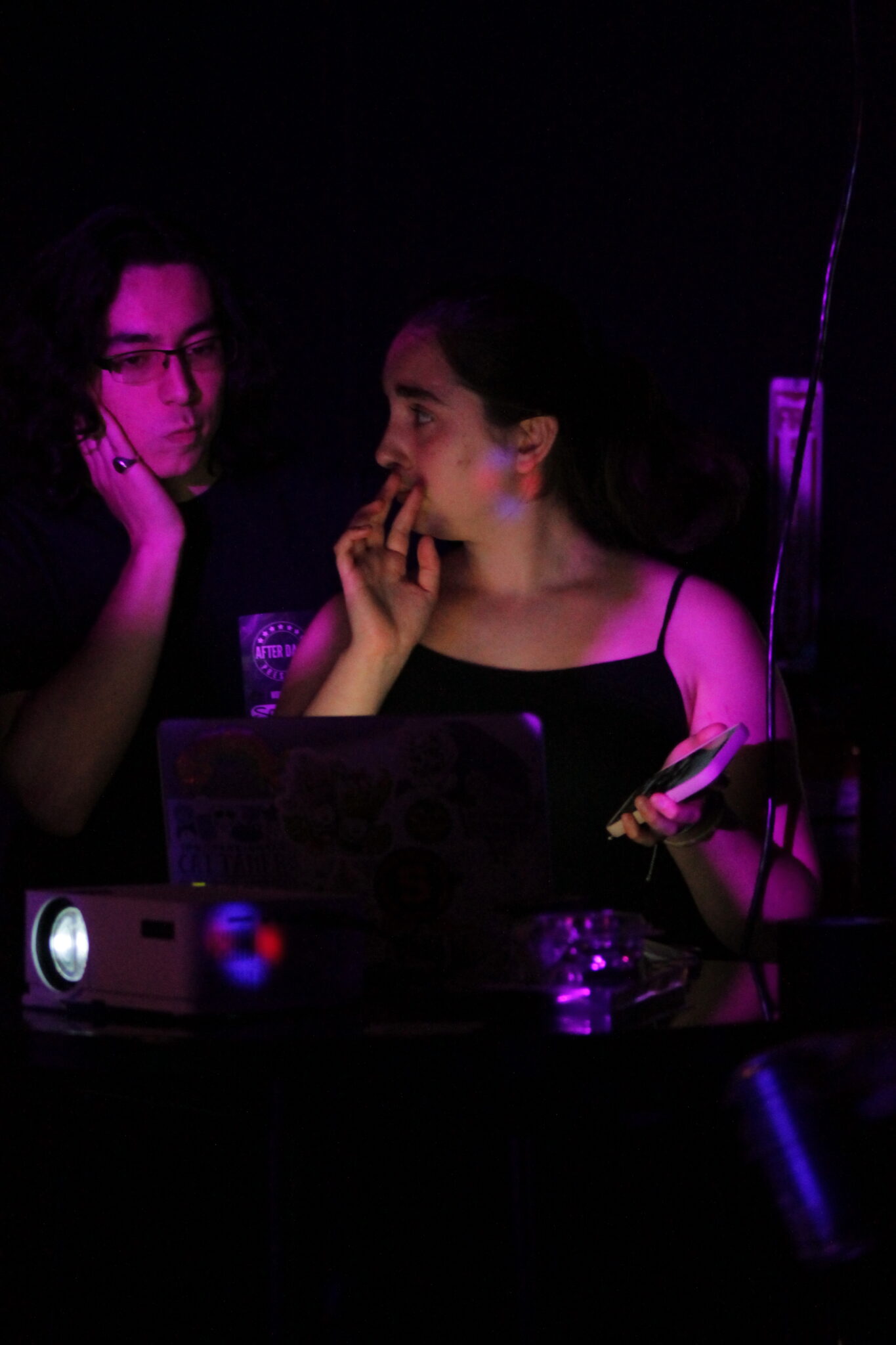 two people stand behind a laptop at a concert