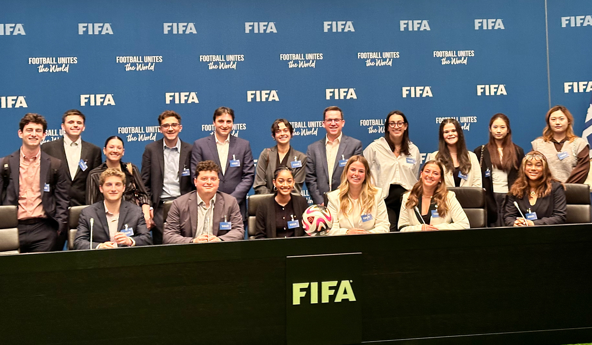 a group of people sit in a press conference room at a table that says Fifa
