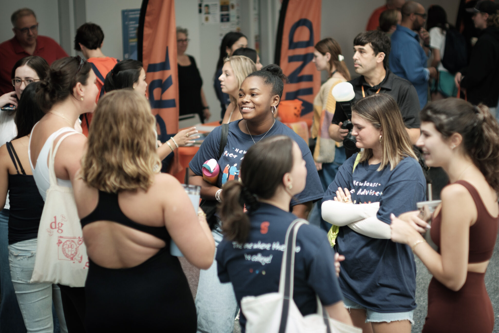 a large group of people mingle and talk in a large hallway