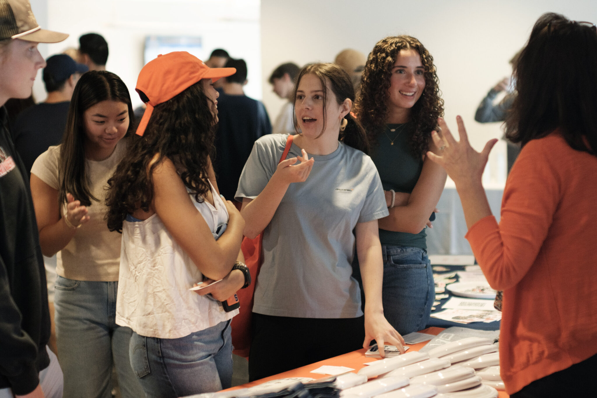 people gather and talk in front of a merch table