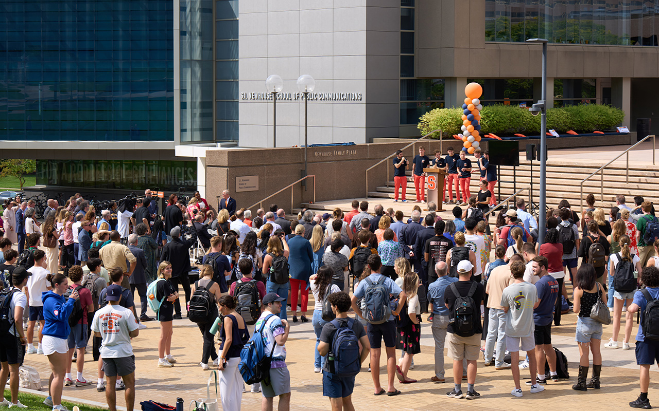 Hundreds of people gather for a ceremony outside of the Newhouse School at Syracuse University