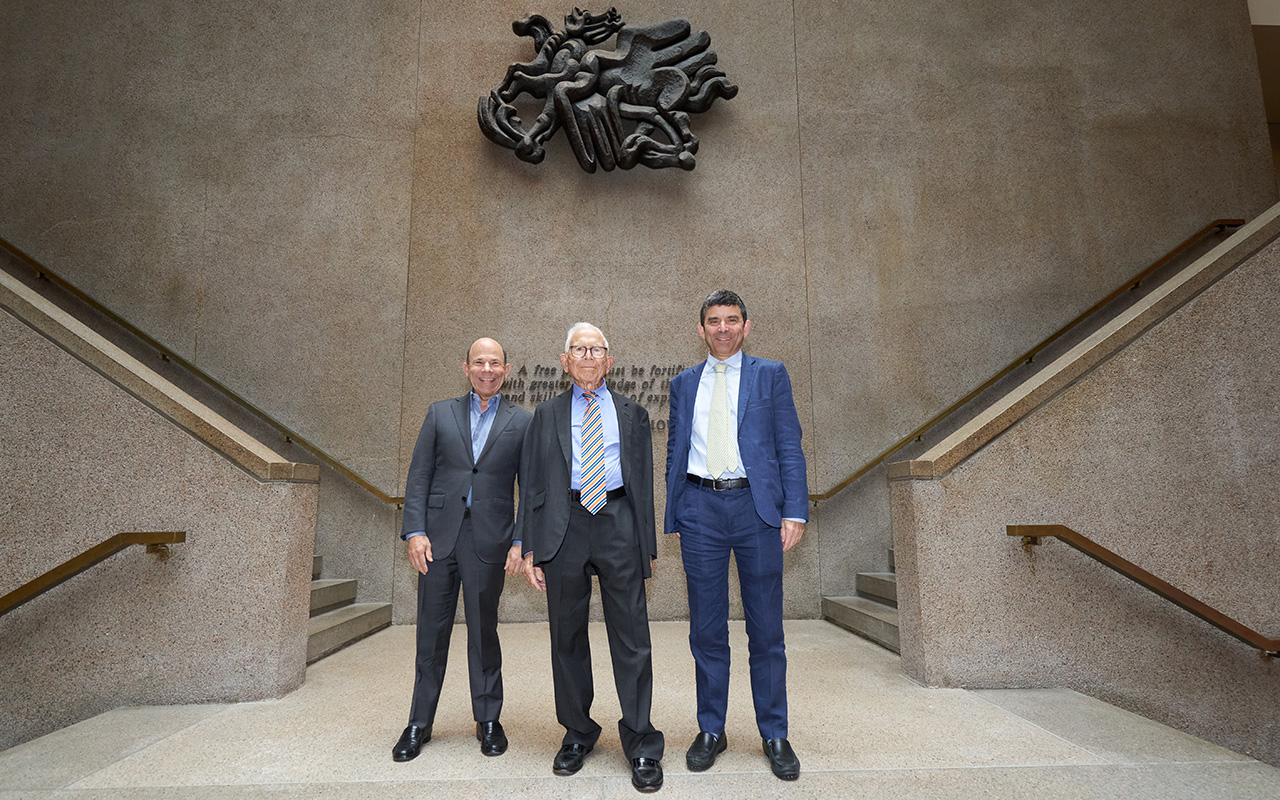 Three men pose for a photo in a building lobby