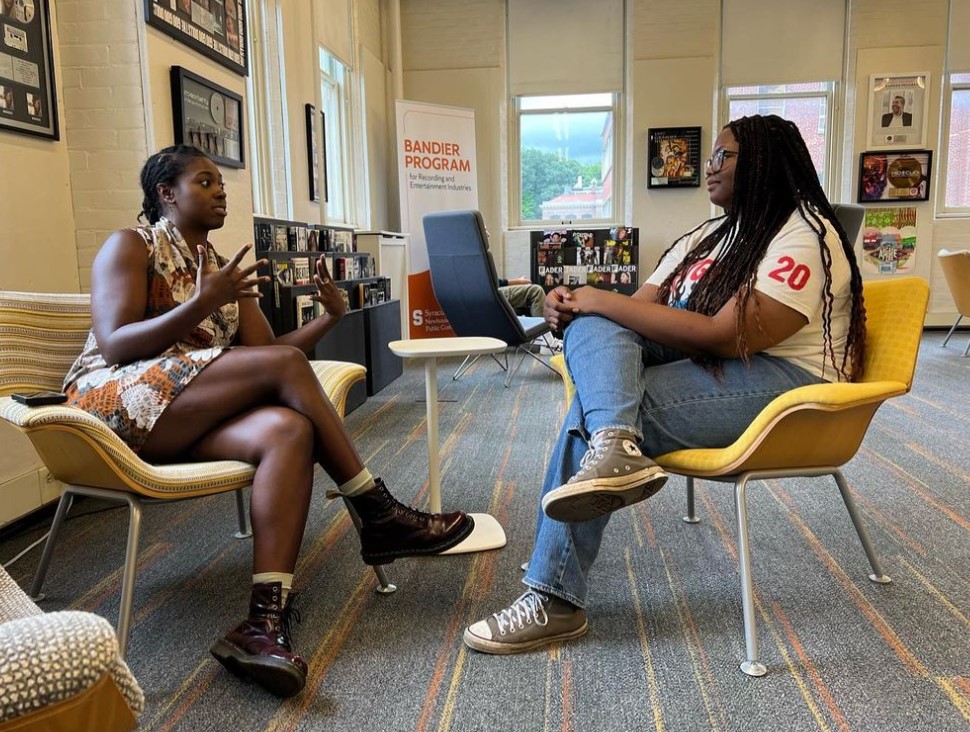 two people sit in chairs across from each other in a room and talk