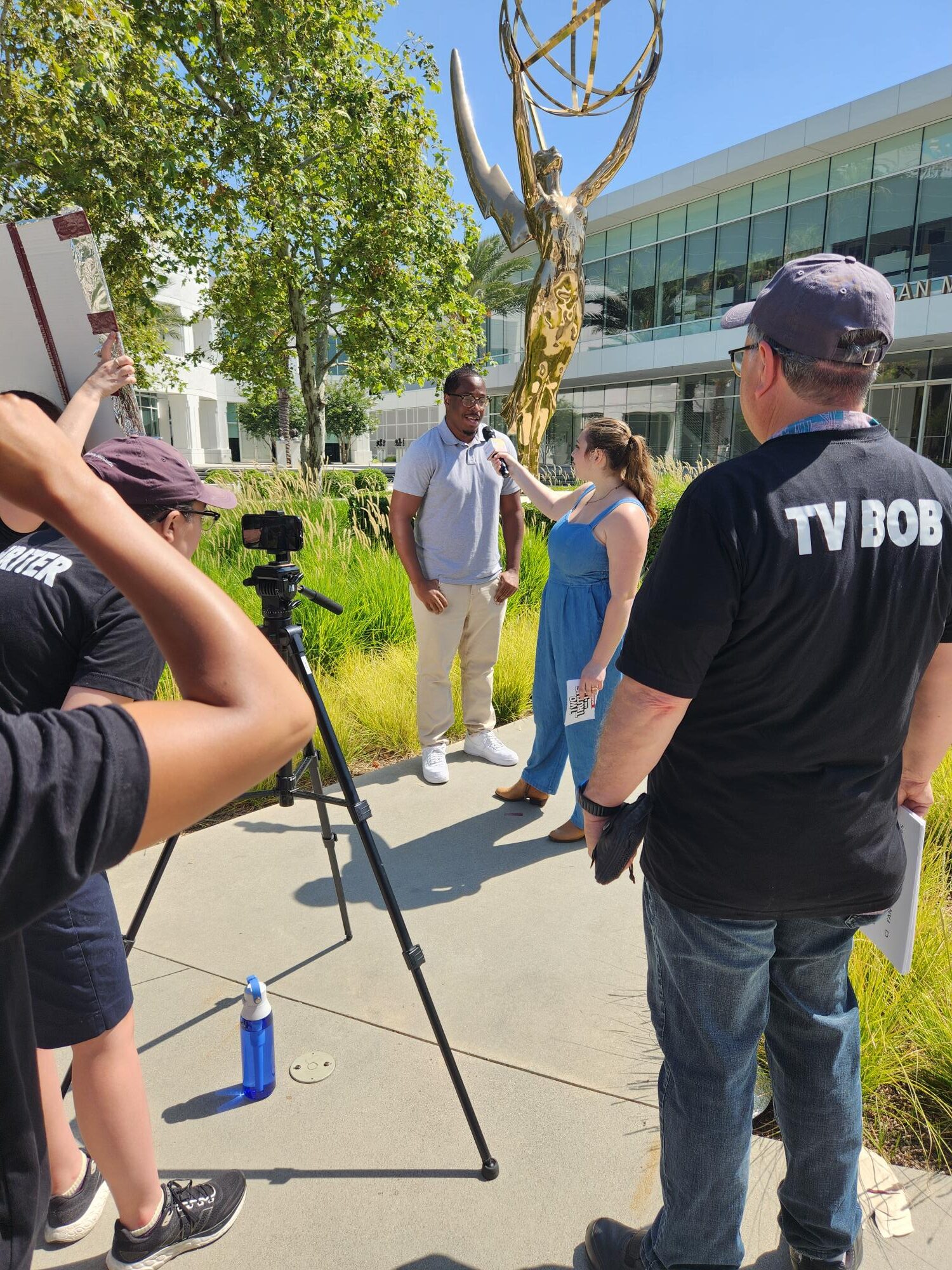 a person is interviewed by a person with a microphone while they are being filmed