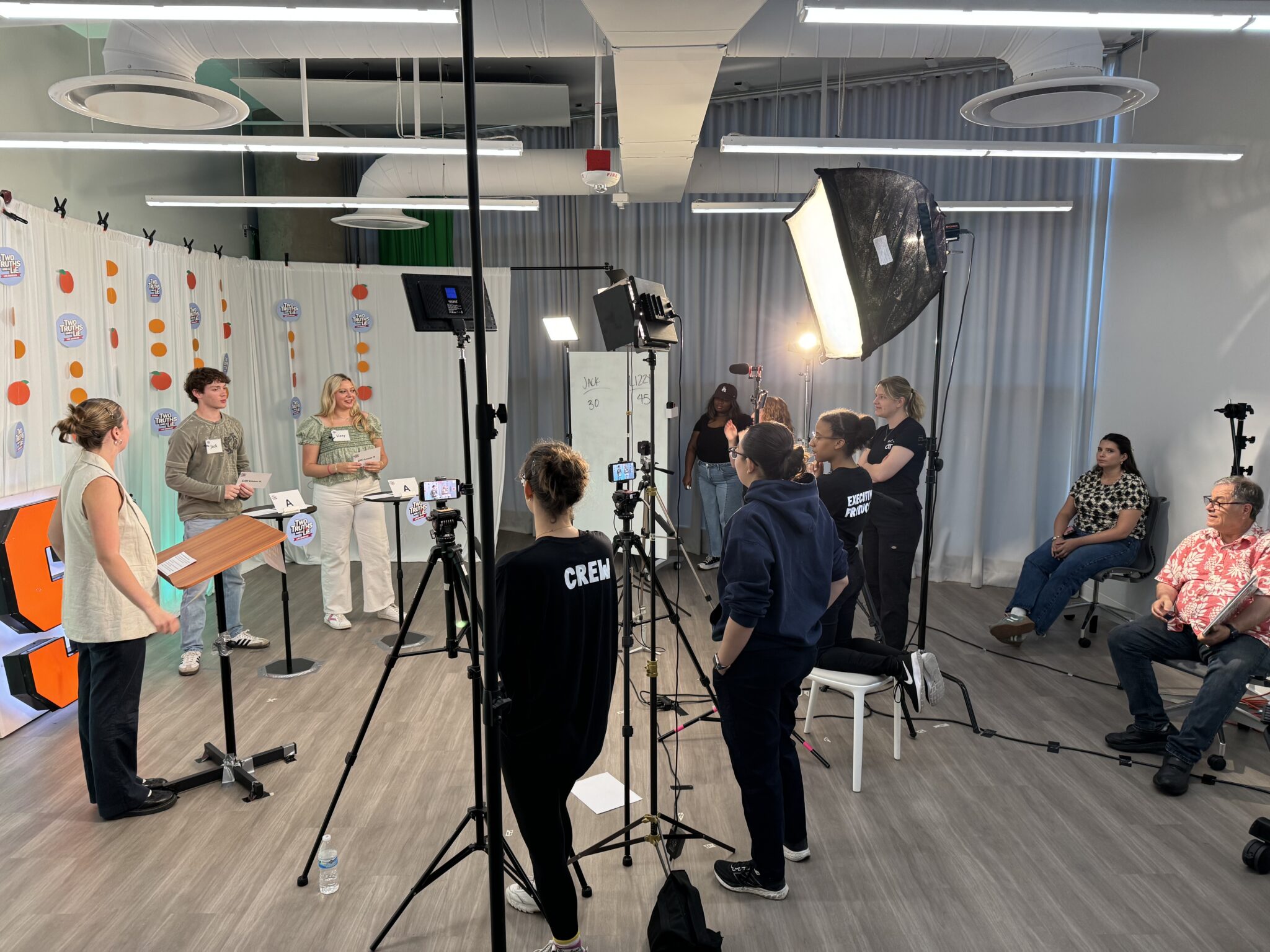 a group of people stand in a studio with filming equipment