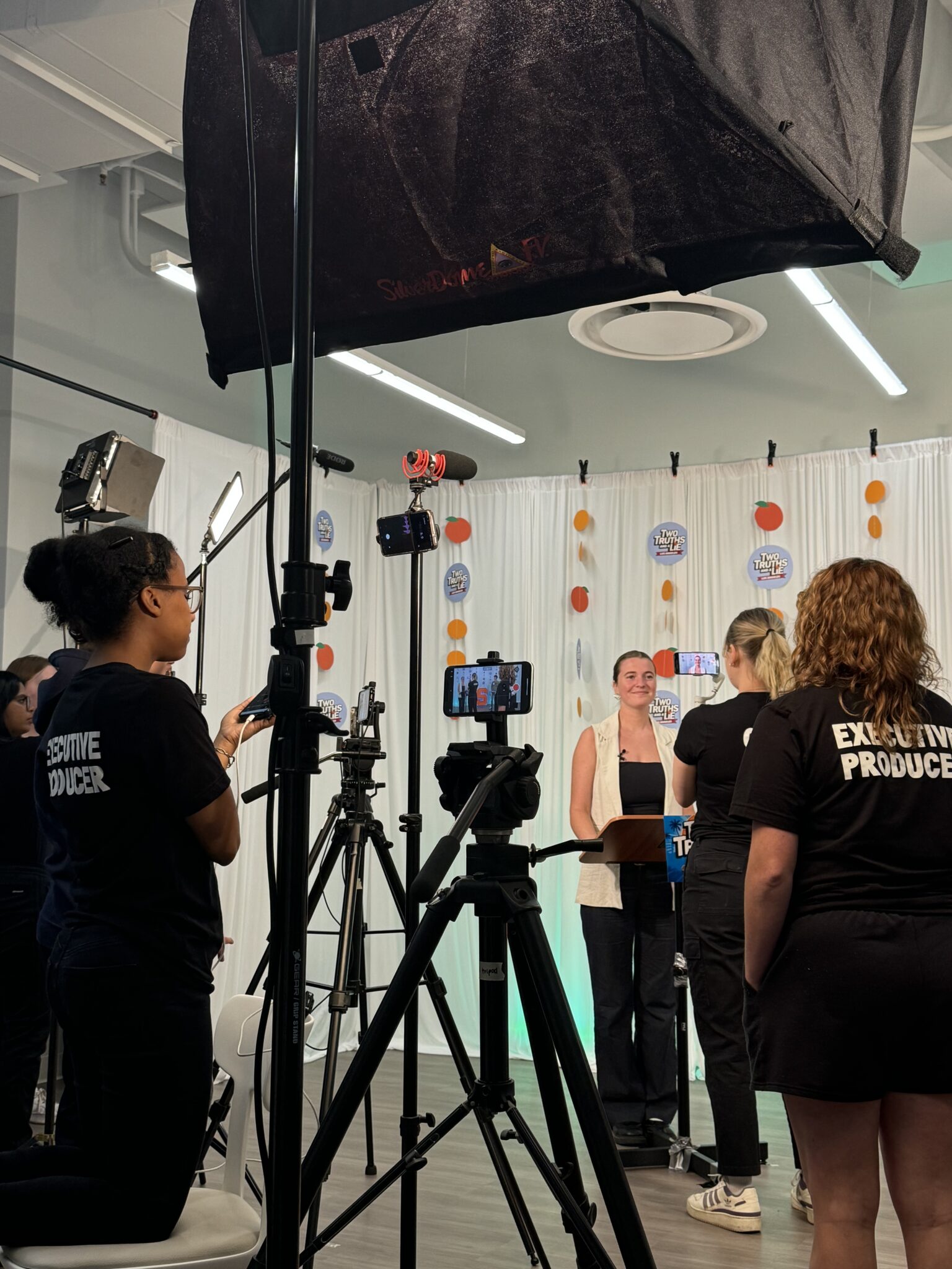 four people stand in a studio with filming equipment