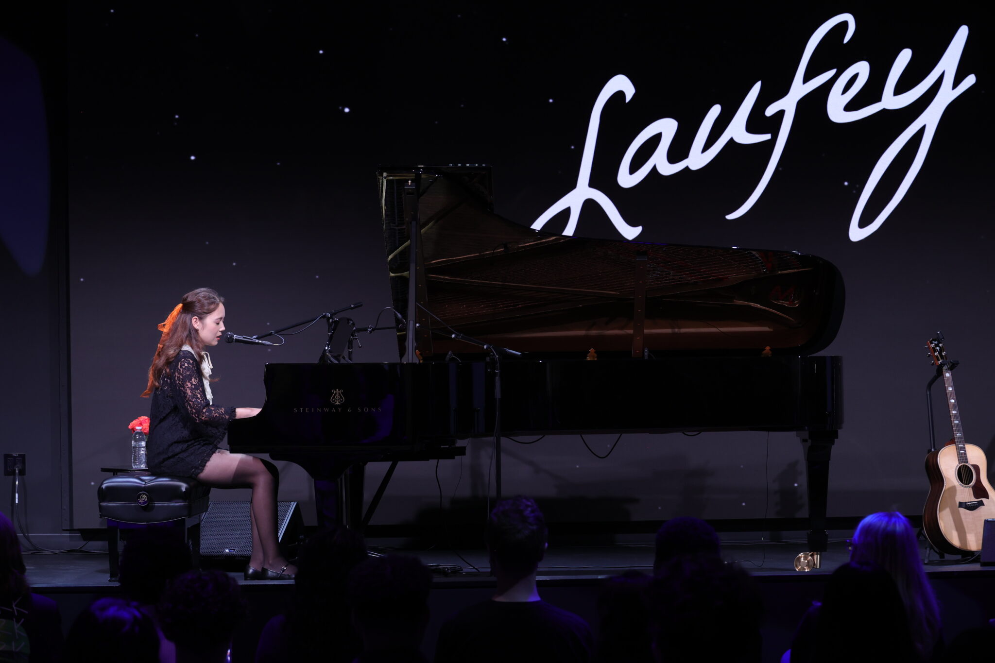 a person sits at a piano on a stage and performs