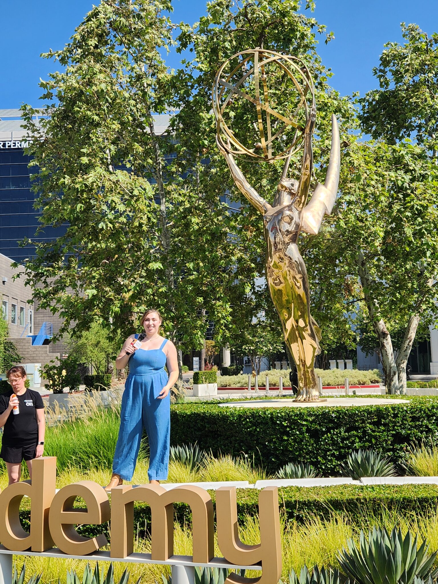 a person stands outside in front of a giant Emmy Award at the Television Academy in Los Angeles, CA