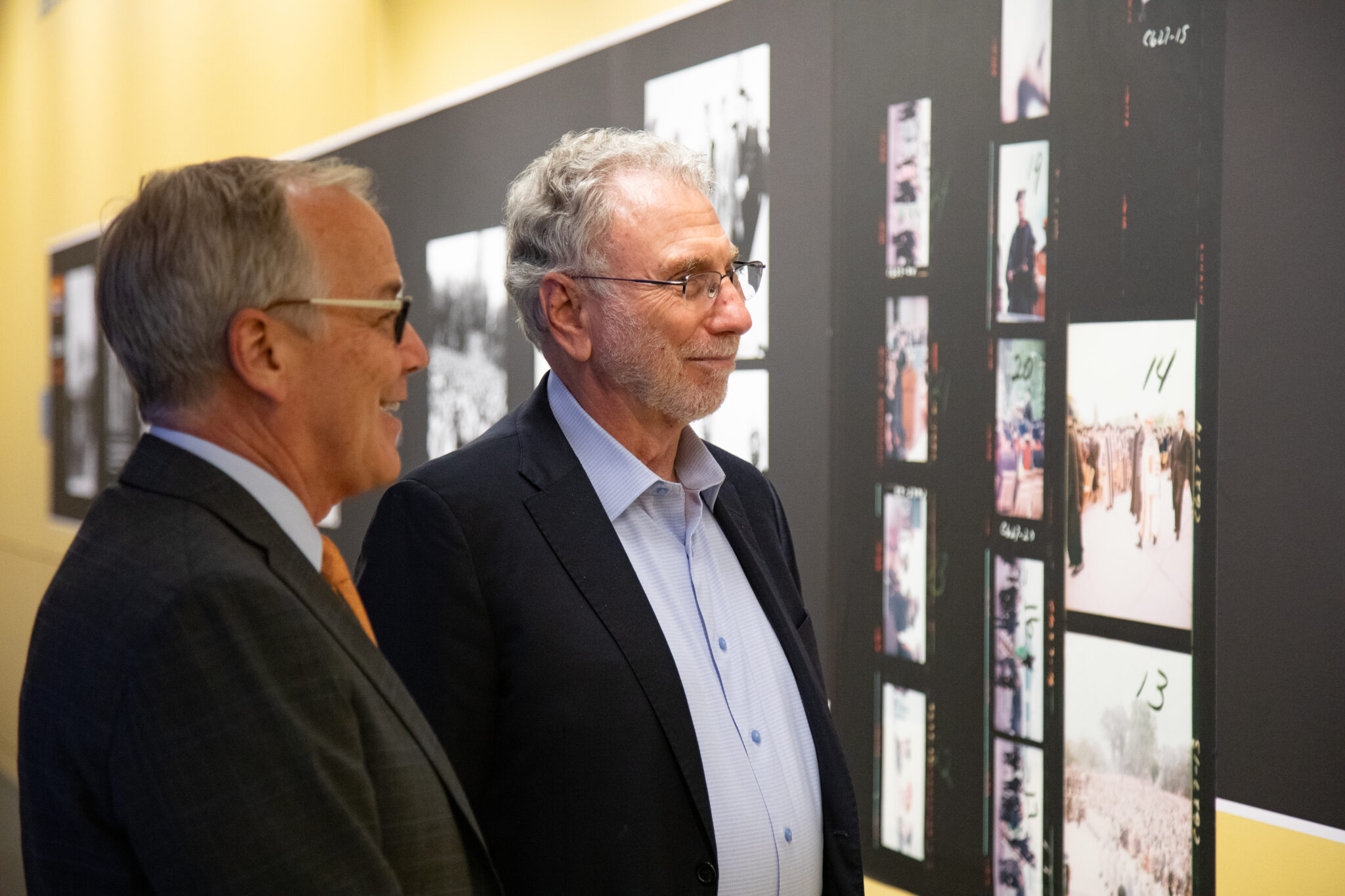 two people look at photos on a wall