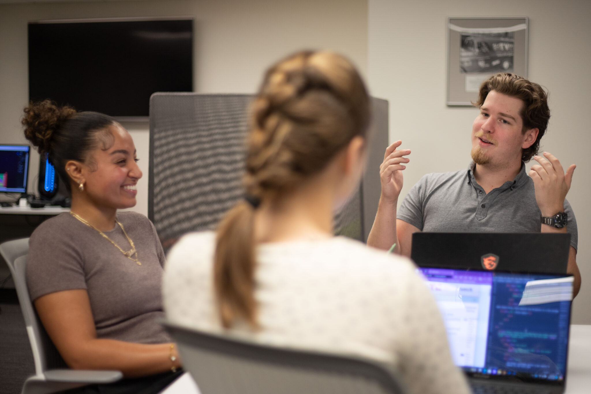 Three advanced media management students talk while sitting at a table.