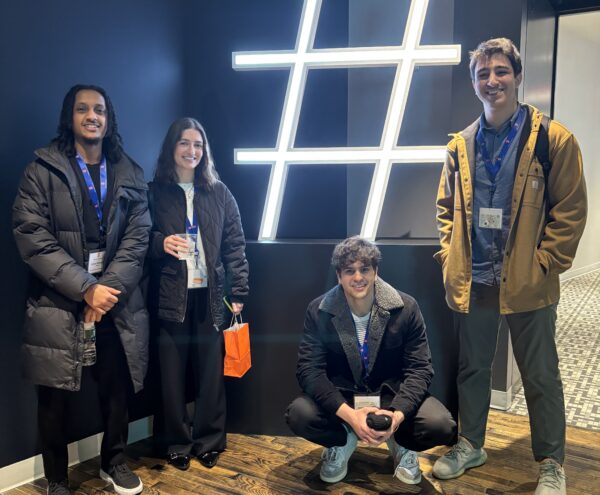 Four advanced media management students pose with a hashtag sign during an immersion trip.