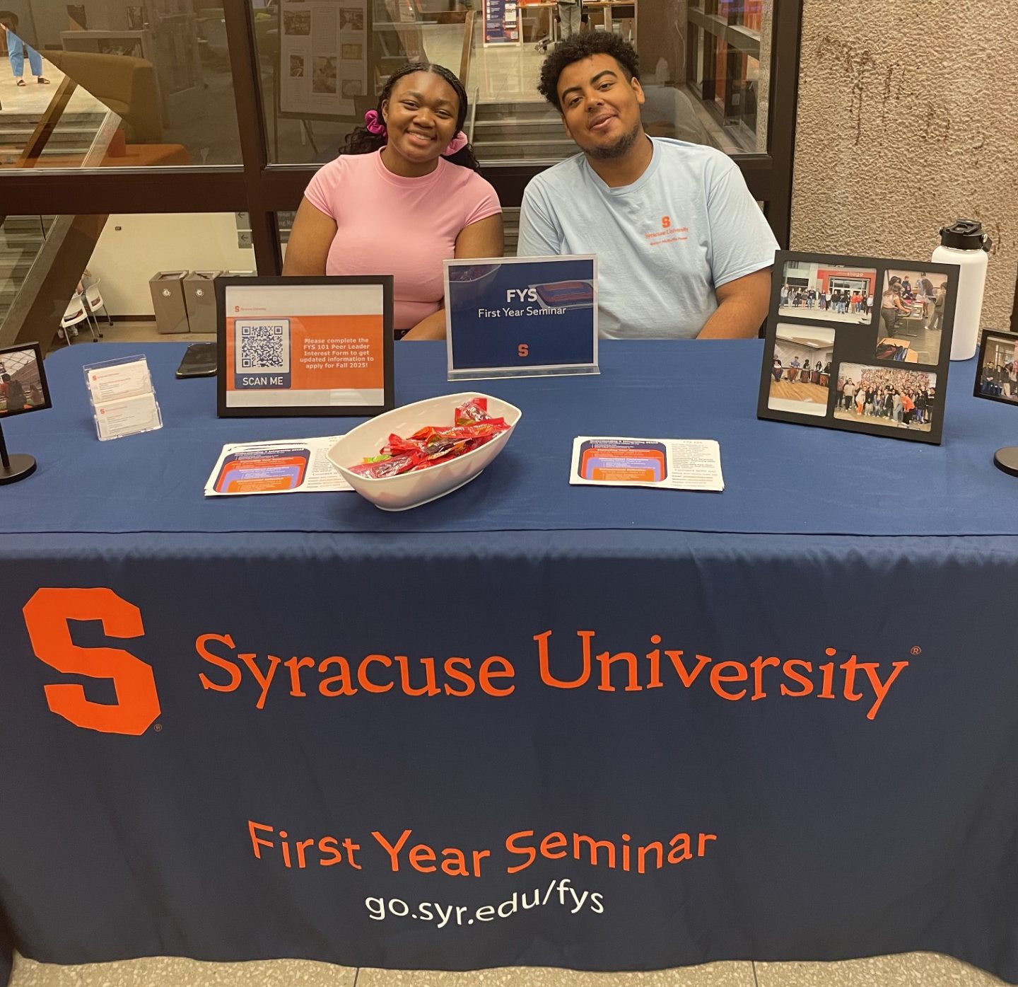 two people sit behind a table and smile