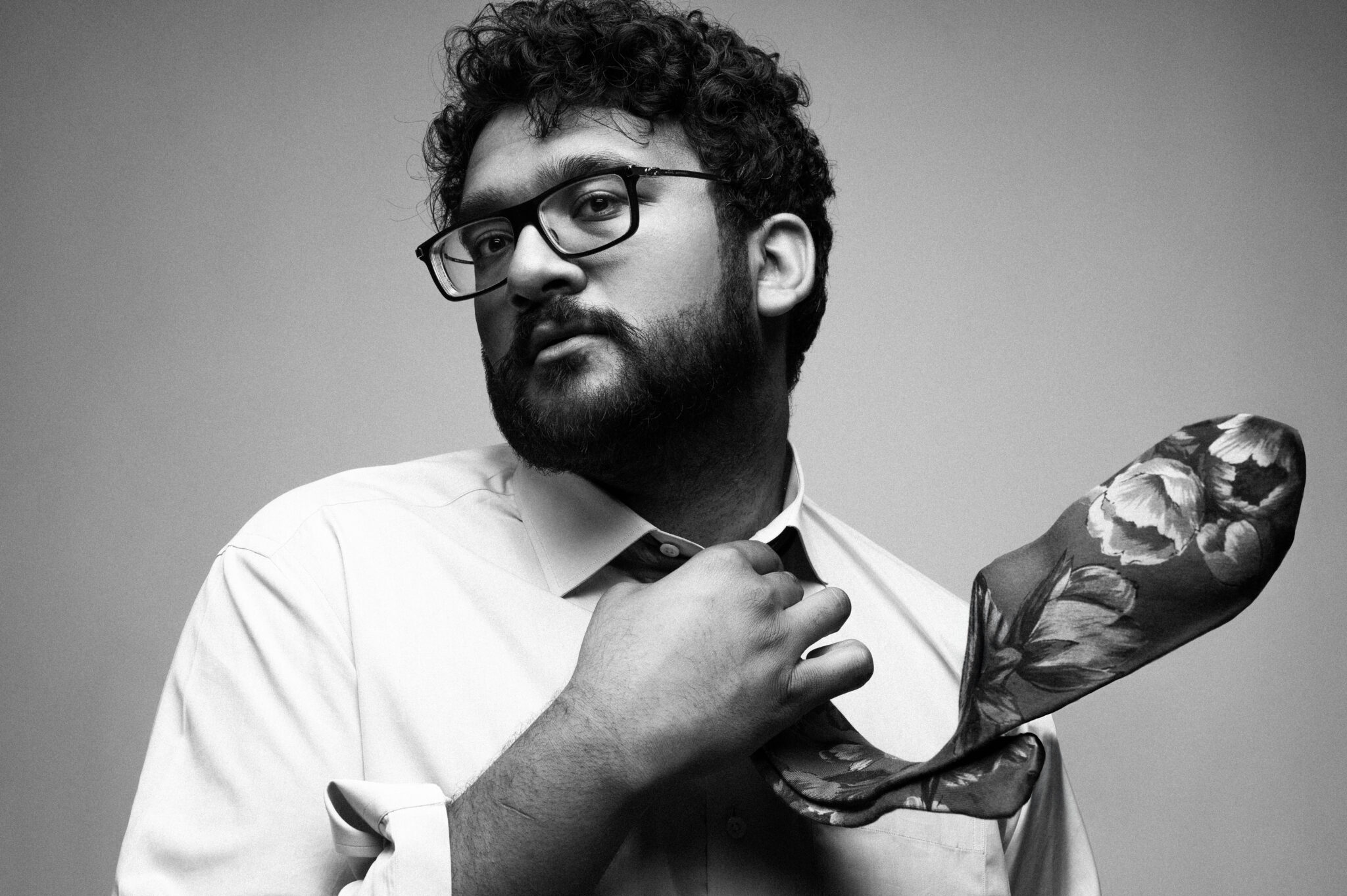 a black and white photo of a person wearing a button down shirt and a tie that's billowing out 