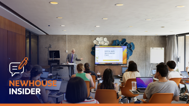 a classroom full of students while a teacher stands at the front