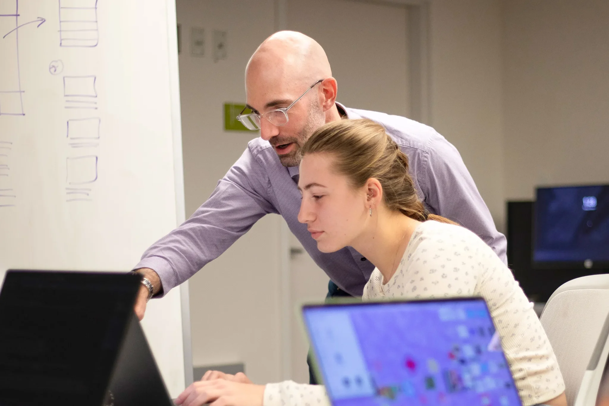 Adam Peruta instructs a student while she works on a laptop